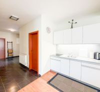 Küche in einer 3-Zimmer-Wohnung mit weißen Schränken und einem Boden in Holzoptik.