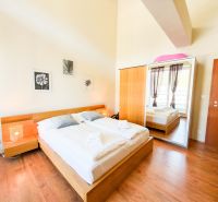 Schlafzimmer mit Bett und großem Schrank, auf einem Boden mit Holzdekor aufgebaut.