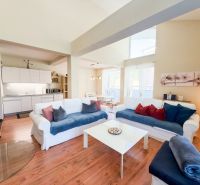 Wohnzimmer in einer 3-Zimmer-Wohnung mit Holzbodenoptik und heller Couch.