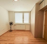 Ein Zimmer mit Holzboden, Ventilator und Stauraum in einer 3-Zimmer-Wohnung.