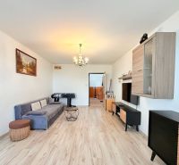 Wohnzimmer in einer 3-Zimmer-Wohnung mit Holzboden, grauem Sofa und Tischfußball.