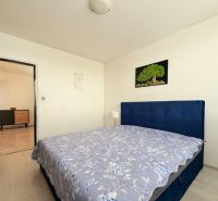 Schlafzimmer mit grauem Boden in einer 3-Zimmer-Wohnung, einfache Möbel und ein Bild an der Wand.