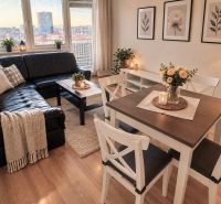 Wohnzimmer in einer 2-Zimmer-Wohnung mit Ledersofa und Holzboden.