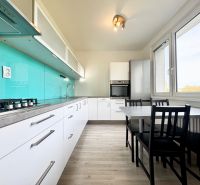 Küche in einer 3-Zimmer-Wohnung mit Holzboden und türkisfarbener Rückwand.