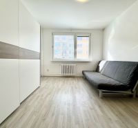 Ein Zimmer in einer 3-Zimmer-Wohnung mit Holzboden, schwarzem Sofa, Kleiderschrank.