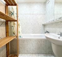 Badezimmer mit Duschvorhang, Holzregal und Waschbecken in einer 3-Zimmer-Wohnung.