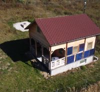 Eine Hütte in Horná Breznica mit Holzverkleidung und rotem Dach auf einem grünen Grundstück.