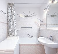 Badezimmer mit Vorhang, Badewanne, Waschbecken und Waschmaschine in einer Einzimmerwohnung.