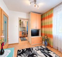 Eine Einzimmerwohnung mit hellen Wänden, orangefarbenen Möbeln und dekorativen Vorhängen.
