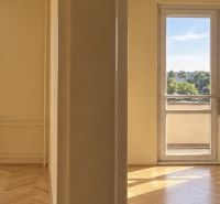 Ein Zimmer mit einem Holzboden in einer 2-Zimmer-Wohnung und Blick auf Komárno.