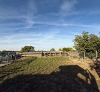 Das Äußere eines Einfamilienhauses in Komárno mit einem eingezäunten Garten und blauem Himmel.