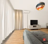 Wohnzimmer in einer Zweizimmerwohnung mit Sofa, Fernseher und Vorhängen auf einem Boden mit Holzdekor.