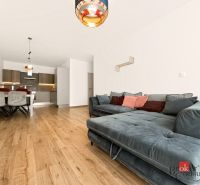 2-Zimmer-Wohnung mit bequemer Couch, Küche im Hintergrund, Boden mit Holzdekor.