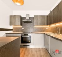 Küche in einer 2-Zimmer-Wohnung mit Holzboden und beleuchteten Schränken.