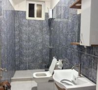 Badezimmer in einer 2-Zimmer-Wohnung mit Keramikfliesen und weißen Sanitäreinrichtungen.