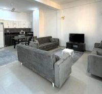 Modernes Wohnzimmer in einer 2-Zimmer-Wohnung mit großer Couch und Küchenzeile.