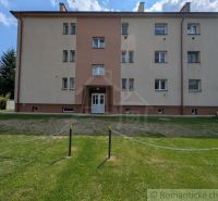 Ein Wohnhaus in Medzilaborce mit einem grünen Hof, dreistöckig und mit hellen Fassaden.