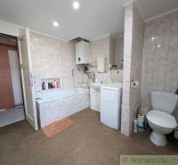 Badezimmer in einer 2-Zimmer-Wohnung mit Badewanne und Waschmaschine, gefliest mit hellen Fliesen.