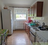 Küche in einer 2-Zimmer-Wohnung mit Keramikfliesen und einem Boden in Holzoptik.