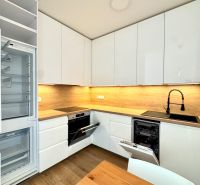 Küche in einer 2-Zimmer-Wohnung mit weißen Schränken und Holzboden-Dekor.