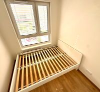 Schlafzimmerbereich mit einem Bettrahmen und einem Boden in Holzoptik in einer Zweizimmerwohnung.