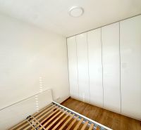 Schlafzimmer in einer 2-Zimmer-Wohnung mit Holzboden und einem großen Schrank.