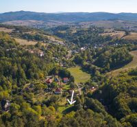 Luftaufnahme von Erholungsgrundstücken in Štiavnické Bane, umgeben von grünen Wäldern und Hügeln.
