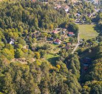 Luftaufnahme von grünen Erholungsgrundstücken in Štiavnické Bane mit Hausdächern.