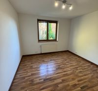 Ein Zimmer in einem Einfamilienhaus mit einem Boden in Holzoptik und einfacher Beleuchtung.