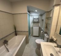 Ein Badezimmer in einem Einfamilienhaus mit Badewanne, Dusche und hellen Fliesen.