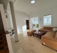 Wohnzimmer in einem Einfamilienhaus mit beigem Sofa und Zugang zur Küche.
