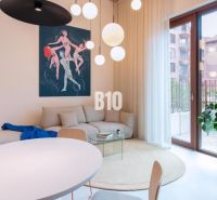 Wohnbereich mit weißen Möbeln, rundem Tisch und Kunst in einer 2-Zimmer-Wohnung.