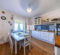 Eine Küche in einem Einfamilienhaus mit weißen Möbeln und einem Boden in Holzoptik.