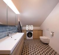 Badezimmer im Einfamilienhaus mit Waschmaschine, Spiegel und Waschbecken, geometrische Fliesen.