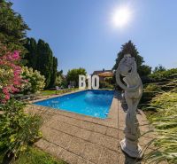 Ein Pool im Garten eines Einfamilienhauses in der Bratislavská-Straße in Malinovo mit Blumen und einer Statue.