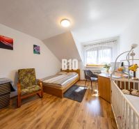 Schlafzimmer im Einfamilienhaus mit Bett, Kinderbett und Boden in Holzoptik.
