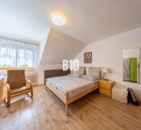 Schlafzimmer in einem Einfamilienhaus mit Holzboden, Bett und Sessel.