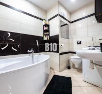 Badezimmer in einer 3-Zimmer-Wohnung mit Badewanne, Toilette und schwarz-weißer Dekoration.