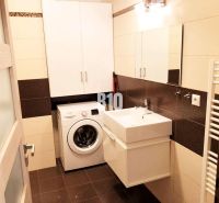 Badezimmer in einer 2-Zimmer-Wohnung mit Schränken, Waschmaschine und Waschbecken.