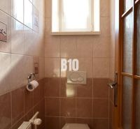 Kleines Badezimmer mit Fenster, Fliesen und Toilette in einem Einfamilienhaus.
