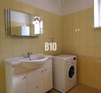 Badezimmer in einem Einfamilienhaus mit Waschmaschine und gelben Fliesen.