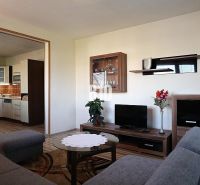 Wohnzimmer in einem Einfamilienhaus mit Blick auf die Küche und einem Boden in Holzoptik.