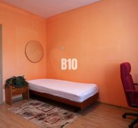 Ein Zimmer in einem Einfamilienhaus mit einem Bett, einem Schreibtisch und einem Boden mit Holzdekor.