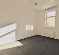 Büroinnenraum mit Teppichboden und Fenster, Blick auf eine Wand und Heizkörper.