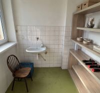 Badezimmer in einem Einfamilienhaus mit Waschbecken, Stuhl und Regalsystem.