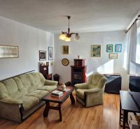 Wohnzimmer in einem Einfamilienhaus mit Sofa und Sessel, Boden mit Holzdekor.