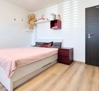 Schlafzimmer in einem Einfamilienhaus mit rosa Bett und Boden in Holzoptik.