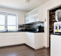 Küche in einem Einfamilienhaus mit weißen Schränken und einem Boden in Holzoptik.