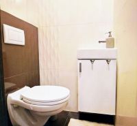 Badezimmer in einem Einfamilienhaus mit Toilette, Waschbecken und Relief-Fliesen.