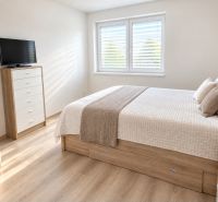 Helles Schlafzimmer mit Bett, Schrank und Holzboden in einem Einfamilienhaus.